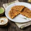 Paneer capsicum paratha with onion stuffing served with curd, pickle, and green chutney