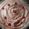 Creamy beetroot hummus topped with olive oil, parsley, and sesame seeds, served with pita bread and fresh vegetable sticks.