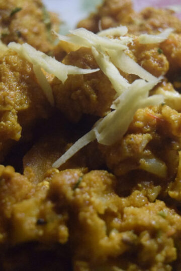 Masala Gobhi curry made with cauliflower, potatoes, tomatoes, and Indian spices served in a traditional bowl