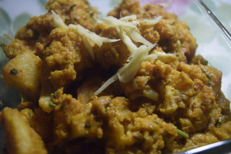 Masala Gobhi curry made with cauliflower, potatoes, tomatoes, and Indian spices served in a traditional bowl