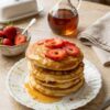 Fluffy egg pancakes stacked with syrup